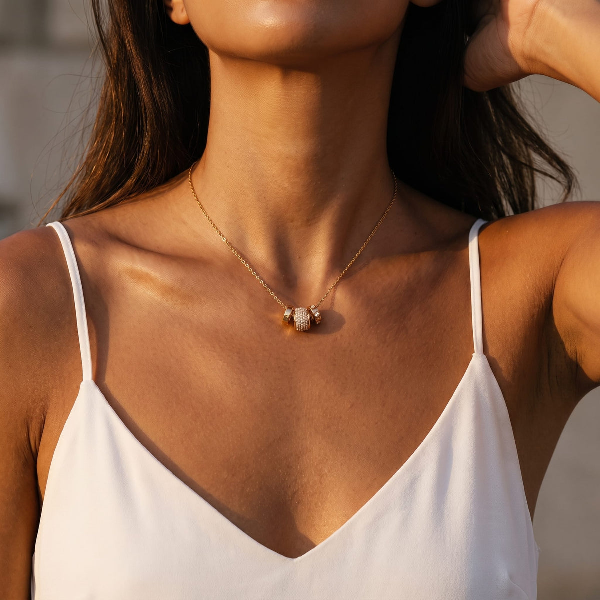 Woman wearing the Fiona pavé rondelle gold necklace at the collarbone in a white camisole top