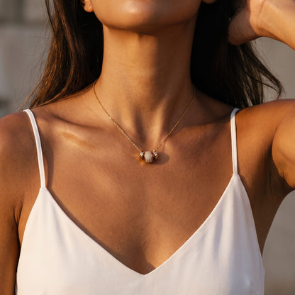 Woman wearing the Fiona pavé rondelle gold necklace at the collarbone in a white camisole top