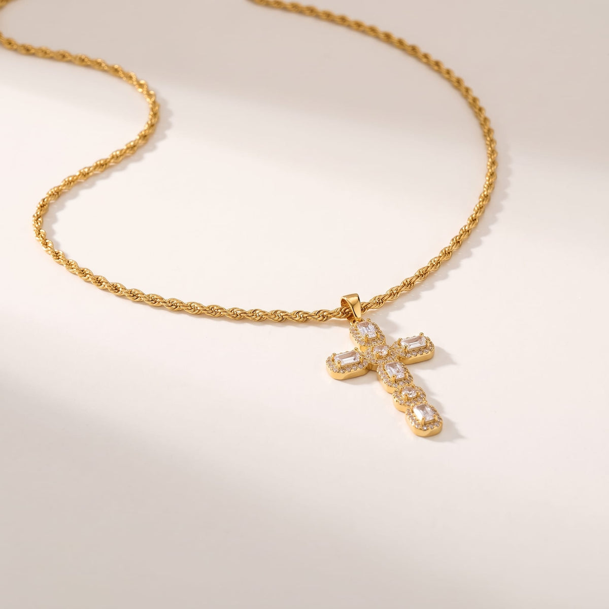 Flavia halo cross gold necklace on a light beige surface in soft warm sunlight
