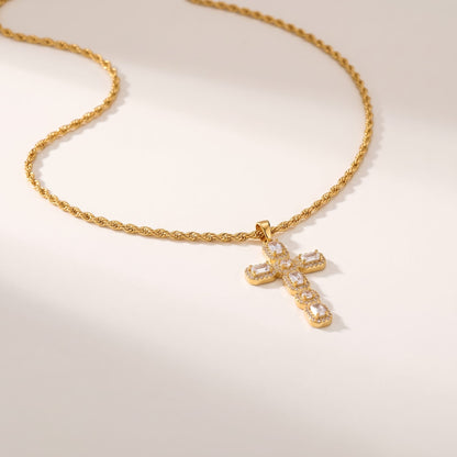 Flavia halo cross gold necklace on a light beige surface in soft warm sunlight