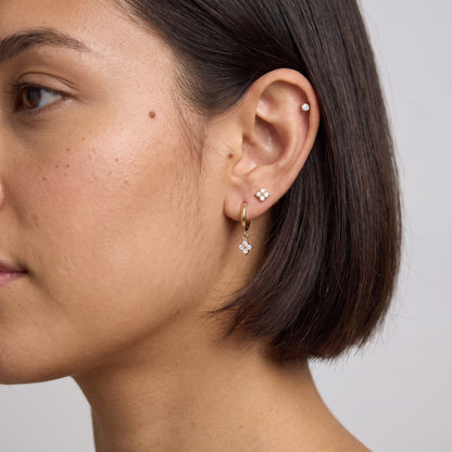 Woman wearing the Fleur clover trio gold earrings on the ear with short dark hair