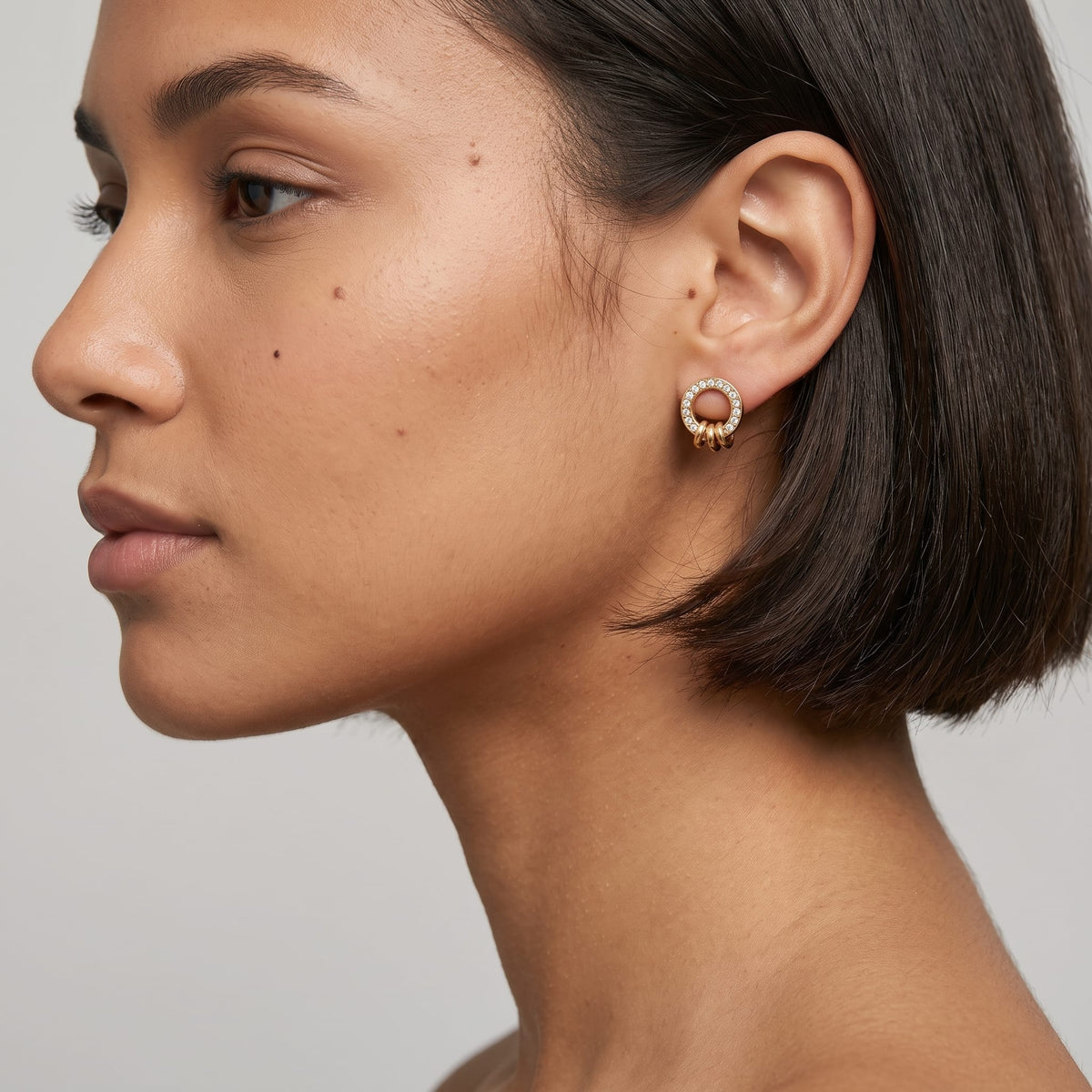 Woman wearing the Gabrielle triple ring gold earrings on the ear in profile with dark bob hair