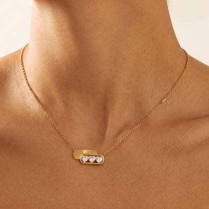 Woman wearing the Ginevra triple heart gold necklace at the collarbone