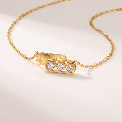 Ginevra triple heart gold necklace on a white surface displaying three heart-cut zircons