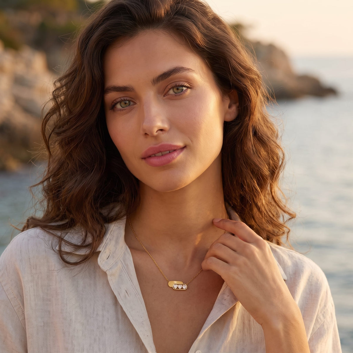 Woman wearing the Ginevra triple heart gold necklace at the collarbone touching her collar wearing a linen shirt