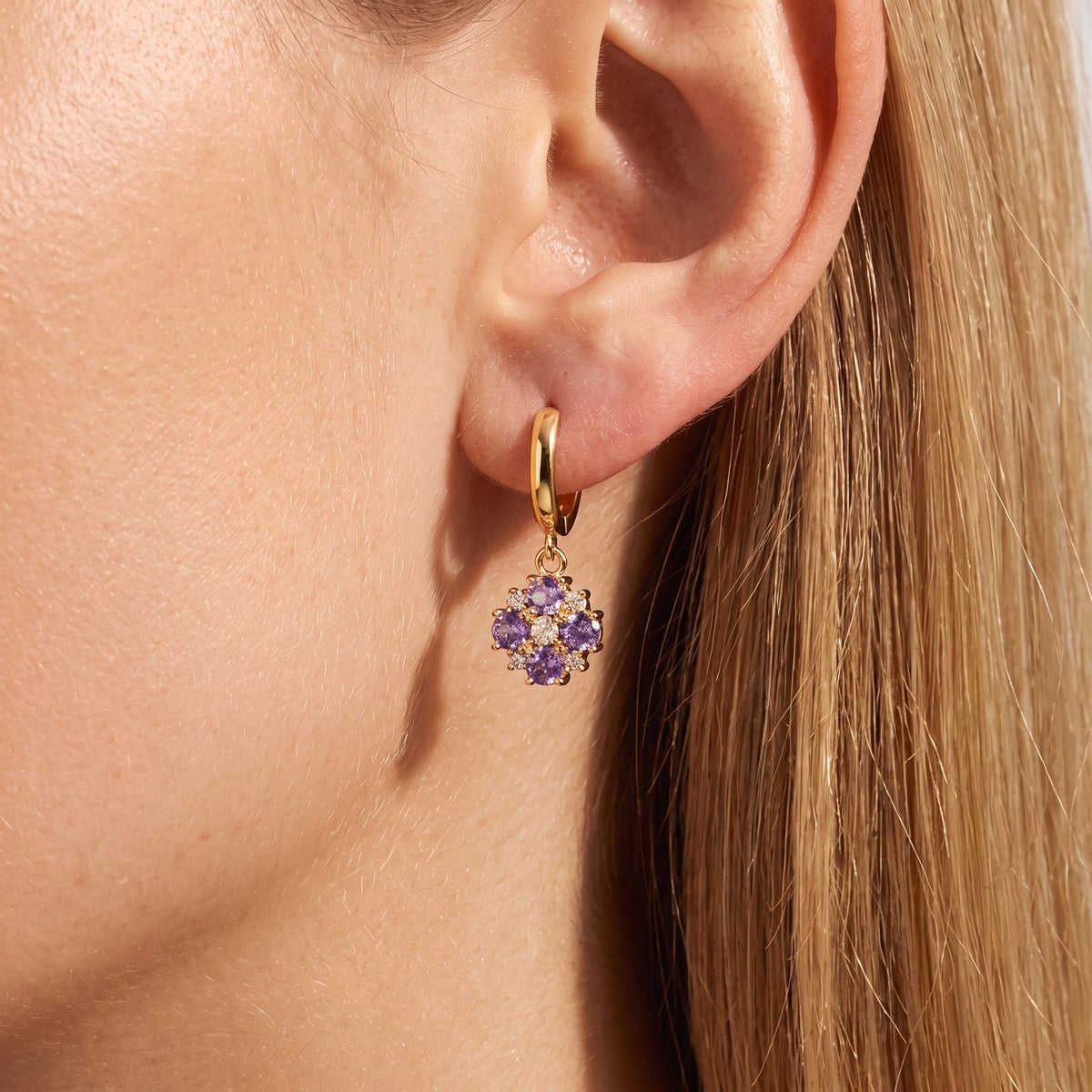 Woman wearing a Giulia gold huggie with a purple and clear crystal cluster drop