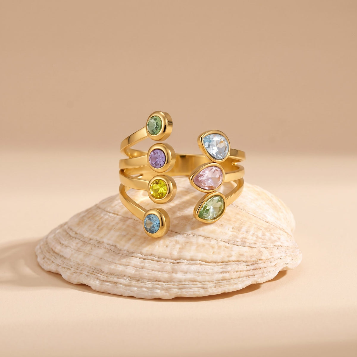 The Giulia pastel crystal gold ring resting on a seashell