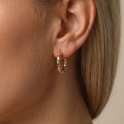 Woman wearing the Hanna gold hoop with a faceted, textured surface catching the light