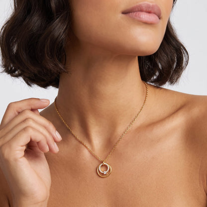 Woman wearing the Héloïse double circle gold necklace at the collarbone raising one hand near neck