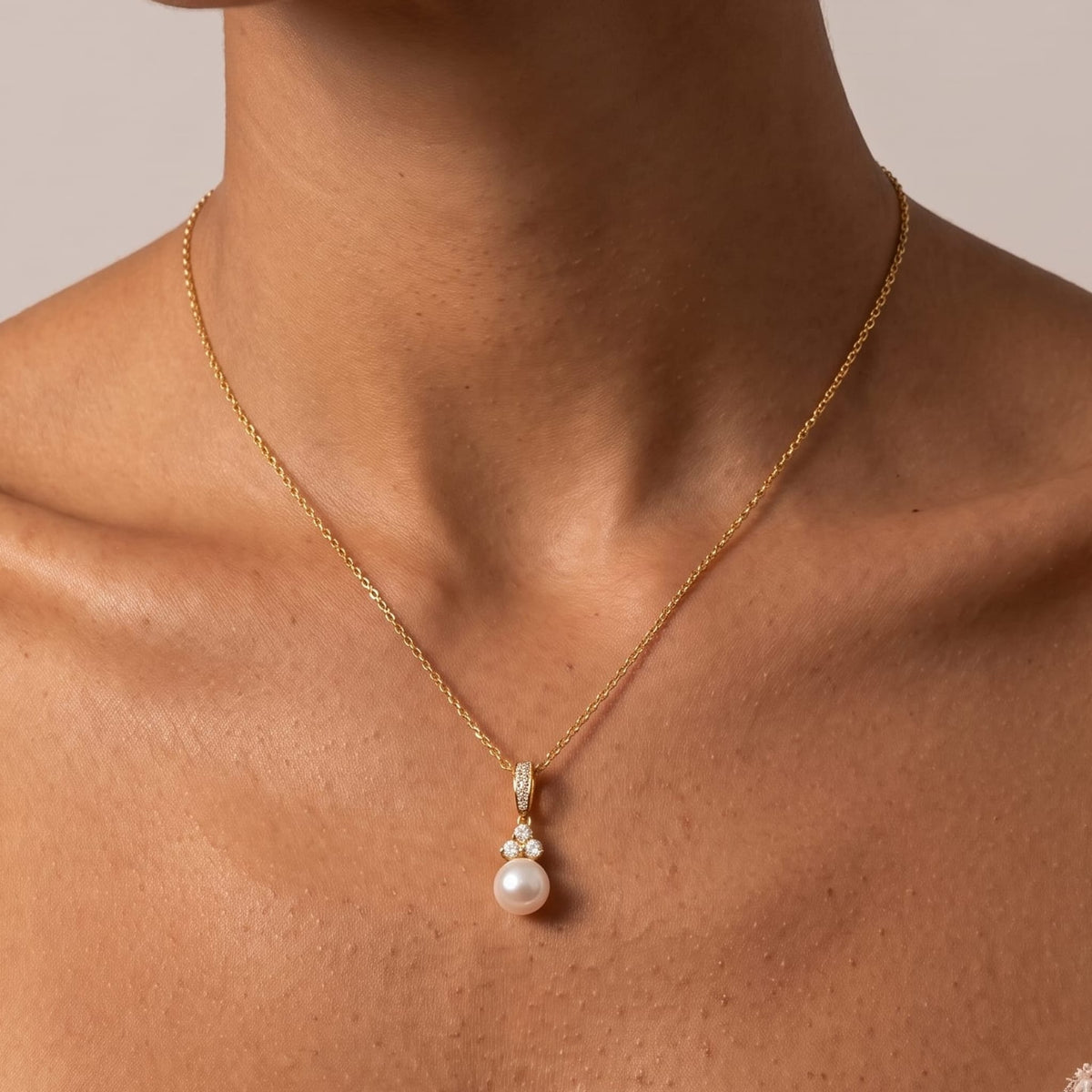 Woman wearing the Hortense pearl pendant gold necklace at the collarbone paired with a lace dress