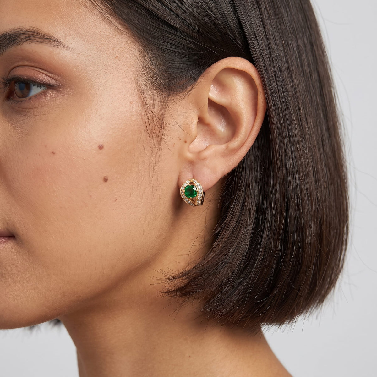 Woman wearing the Ilaria green halo gold earrings on the ear with short dark hair