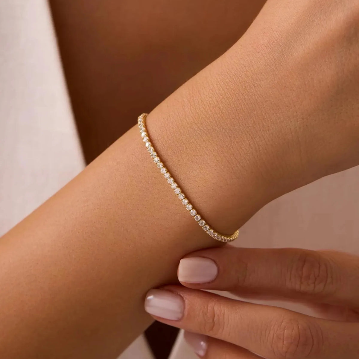 Woman wearing the Amélie Tennis bracelet in gold, a continuous row of zircons around the wrist