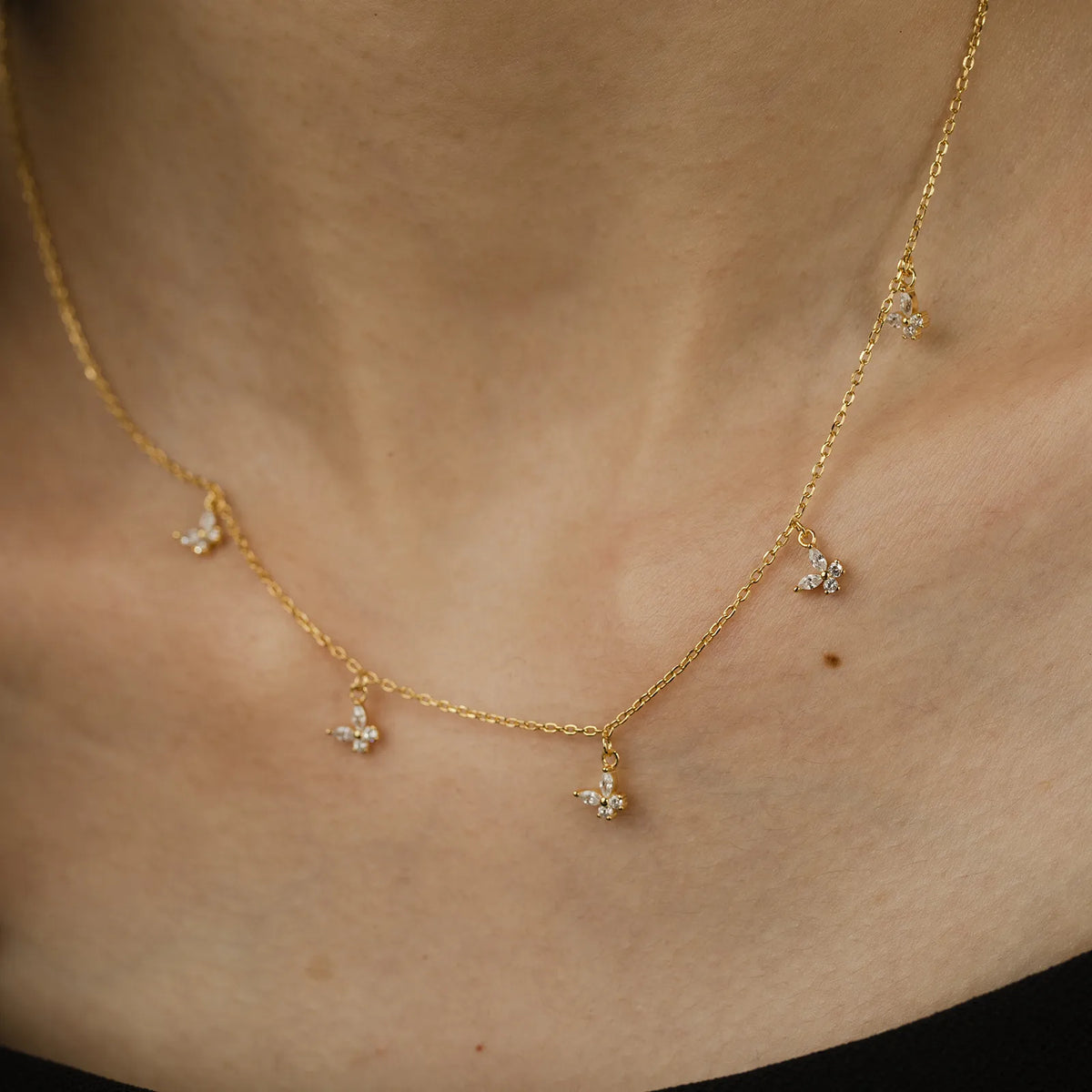 Woman wearing the Amélie crystal butterfly necklace in gold, tiny butterfly charms at the collarbone