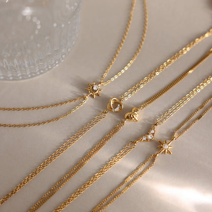 Inès crystal chevron bracelet among double chain charm bracelets on a satin surface