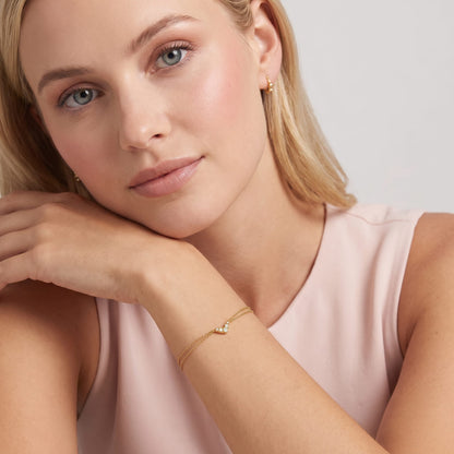 Woman wearing the Inès crystal chevron gold bracelet on the wrist resting against her cheek