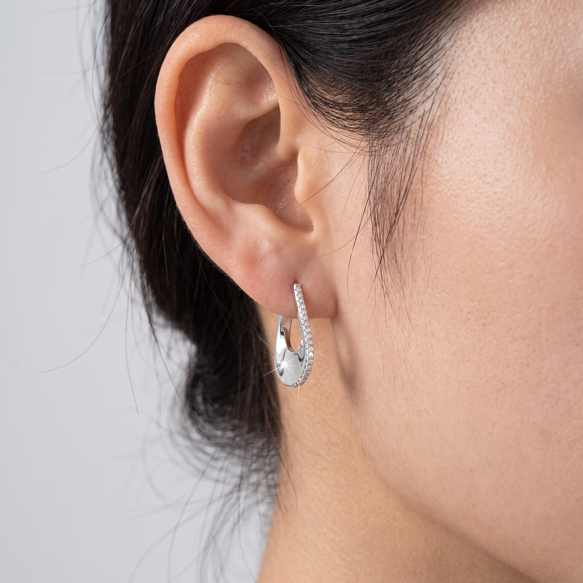 Woman wearing an Isabella silver teardrop hoop with a line of crystals along one edge