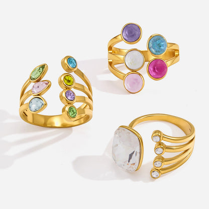 Three coloured-stone gold rings on white: the Isabella rainbow stone ring at the top right