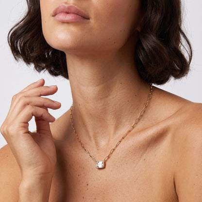 Woman wearing the Isabelle emerald cut gold necklace at the collarbone with hand raised