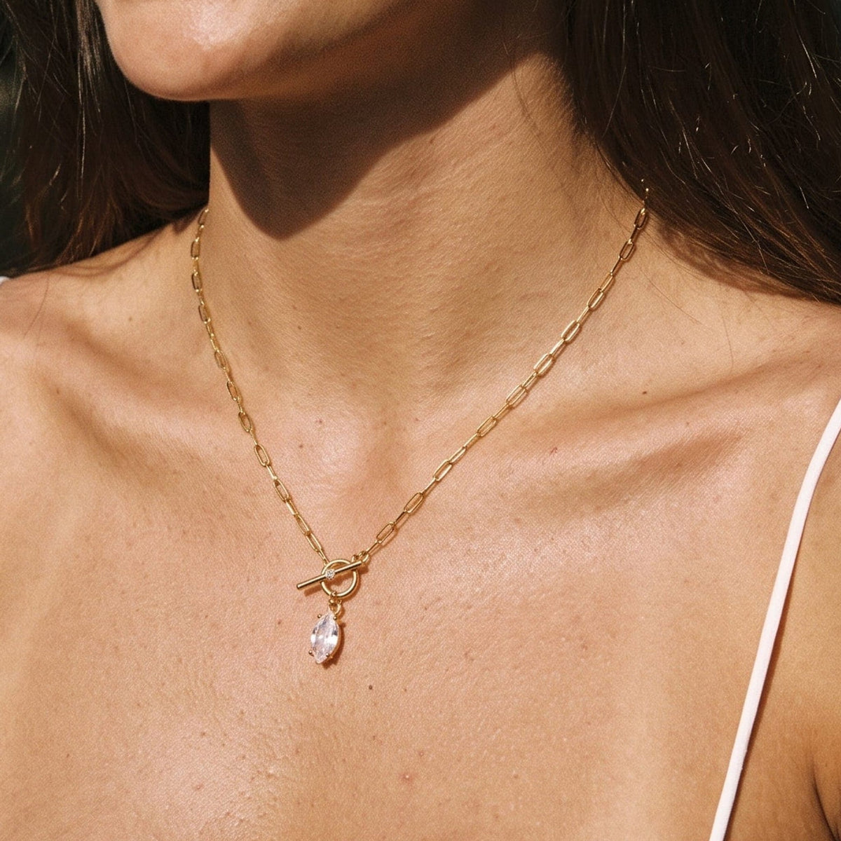 Woman wearing the Isabelle marquise toggle gold necklace at the collarbone, smiling in sunlight