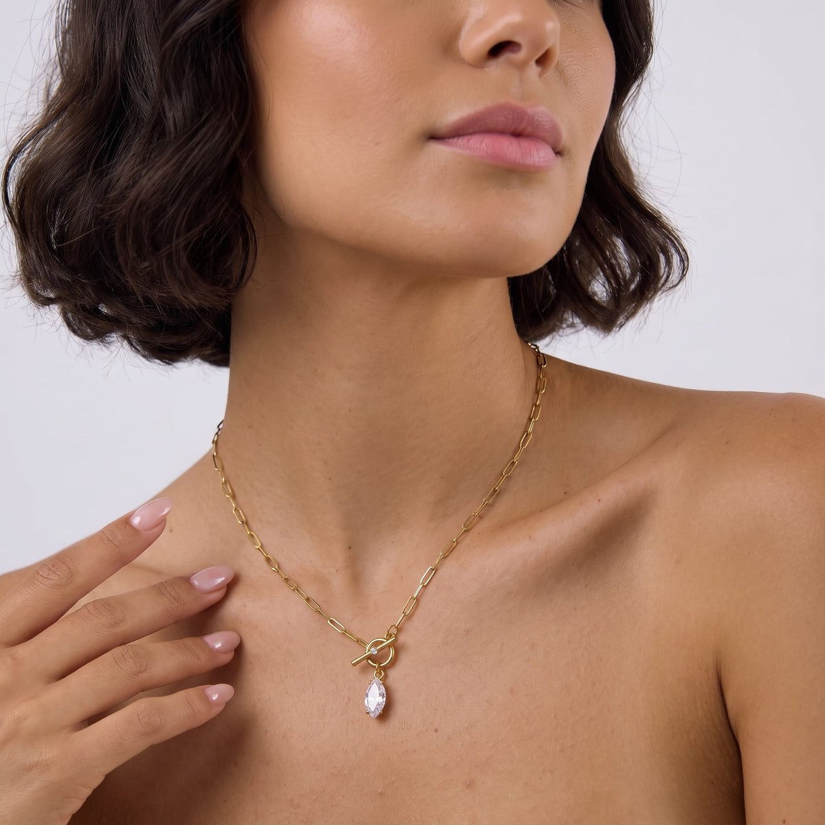 Woman wearing the Isabelle marquise toggle gold necklace at the collarbone, holding her hand near her neck