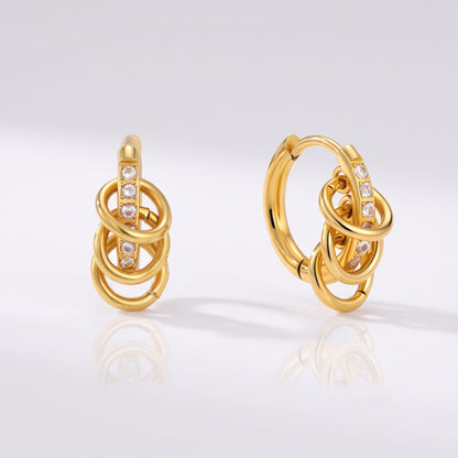 Joséphine triple loop gold earrings on a reflective white surface displaying sparkling stone details