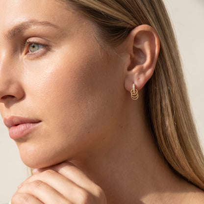 Woman wearing the Joséphine triple loop gold earrings on the ear with hand resting on chin