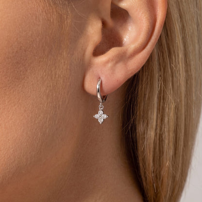 Woman wearing a Juliette silver huggie with a clear crystal clover charm below the lobe