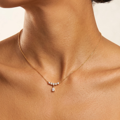 Woman wearing the Juliette crystal arc gold necklace at the collarbone, featuring a teardrop crystal pendant