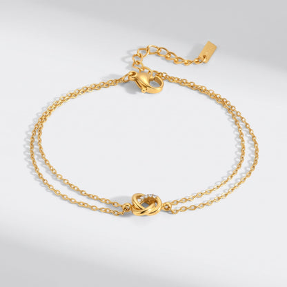 Juliette love knot gold bracelet on a plain white surface displaying its delicate double chain link