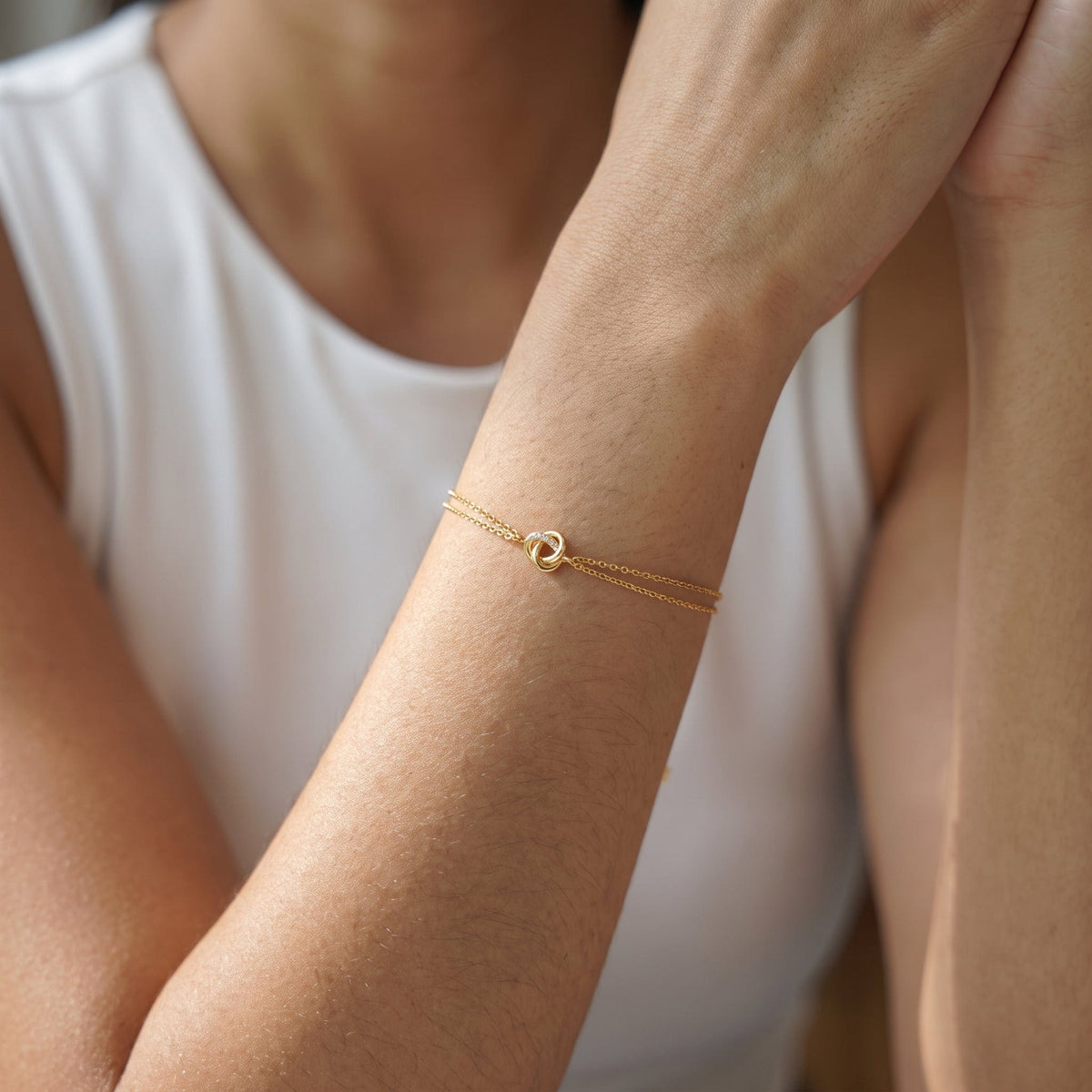 Wider view of a woman wearing the Juliette love knot gold bracelet on the wrist