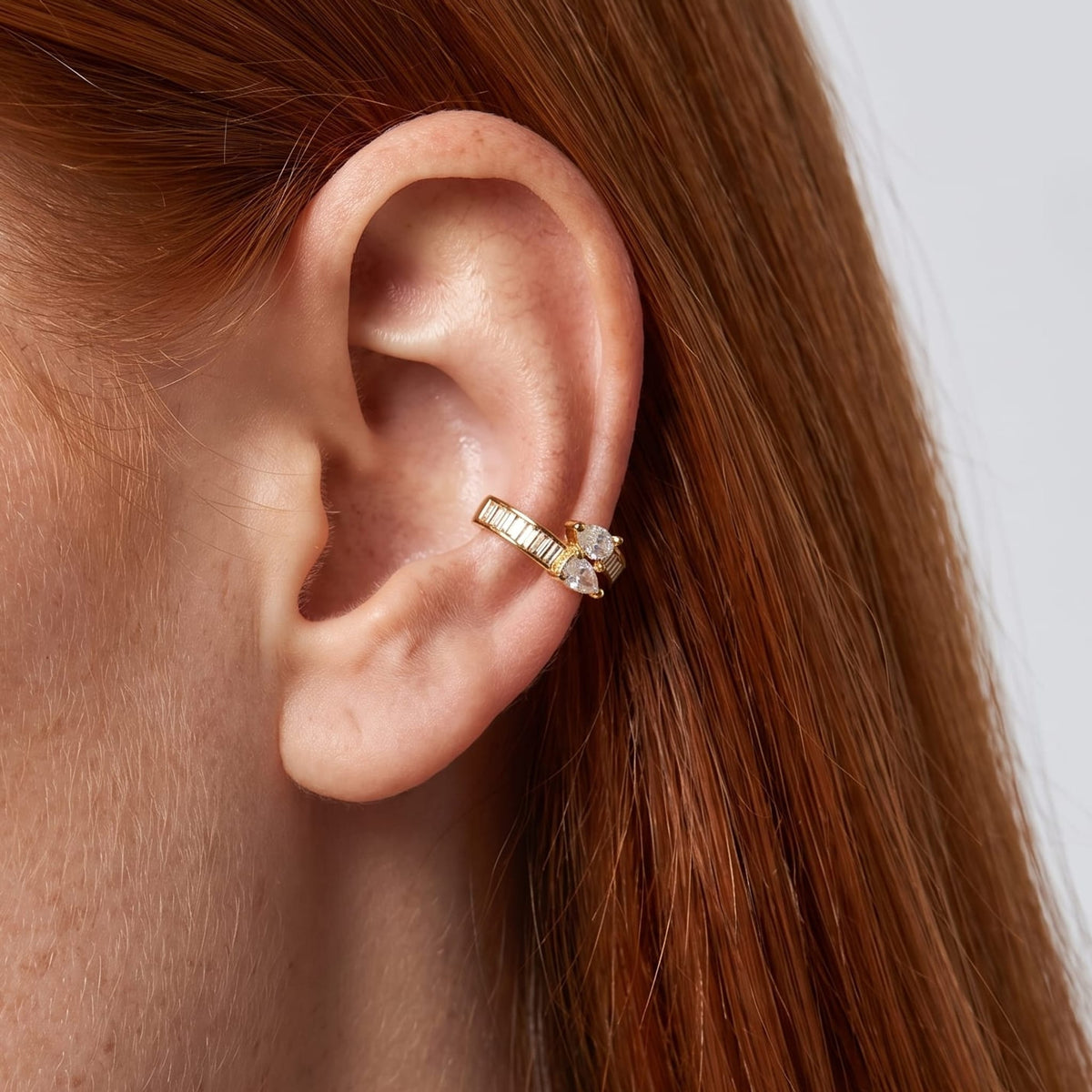 Woman wearing the Laure baguette gold ear cuffs on her ear with red hair