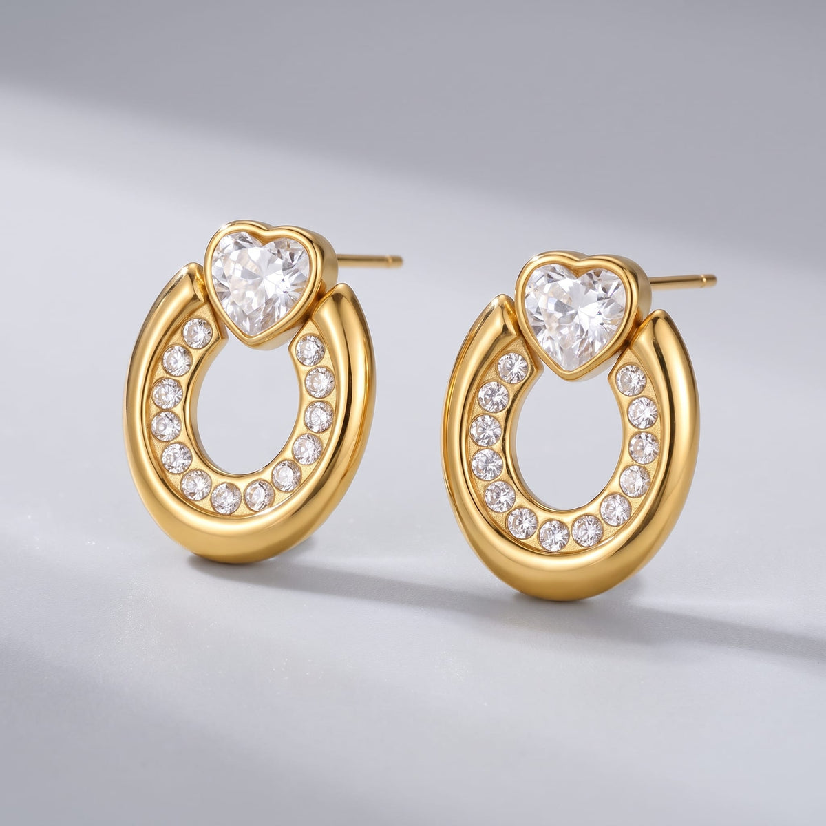 Léonore horseshoe crystal gold earrings on a light gray reflective surface