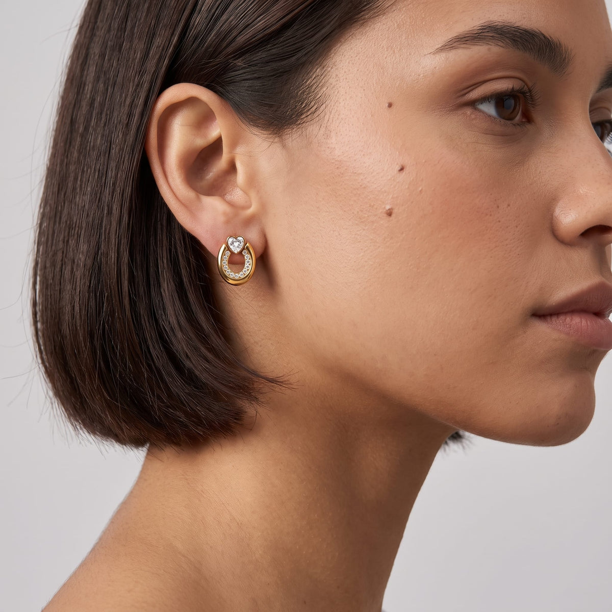Woman wearing the Léonore horseshoe crystal gold earrings on her ear with short dark hair