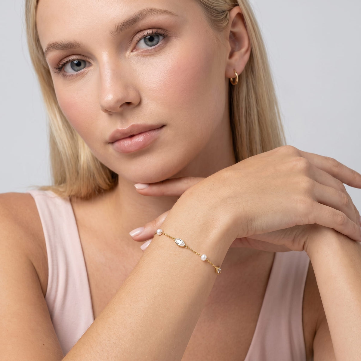 Woman wearing the Liana marquise pearl gold bracelet on the wrist in a pink top