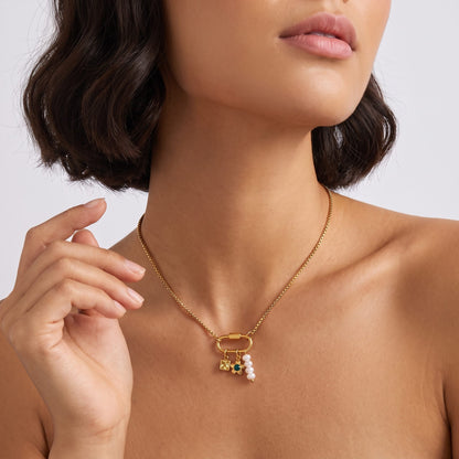 Woman with a dark bob wearing the Lilou daisy charm gold necklace, one hand raised near her neck