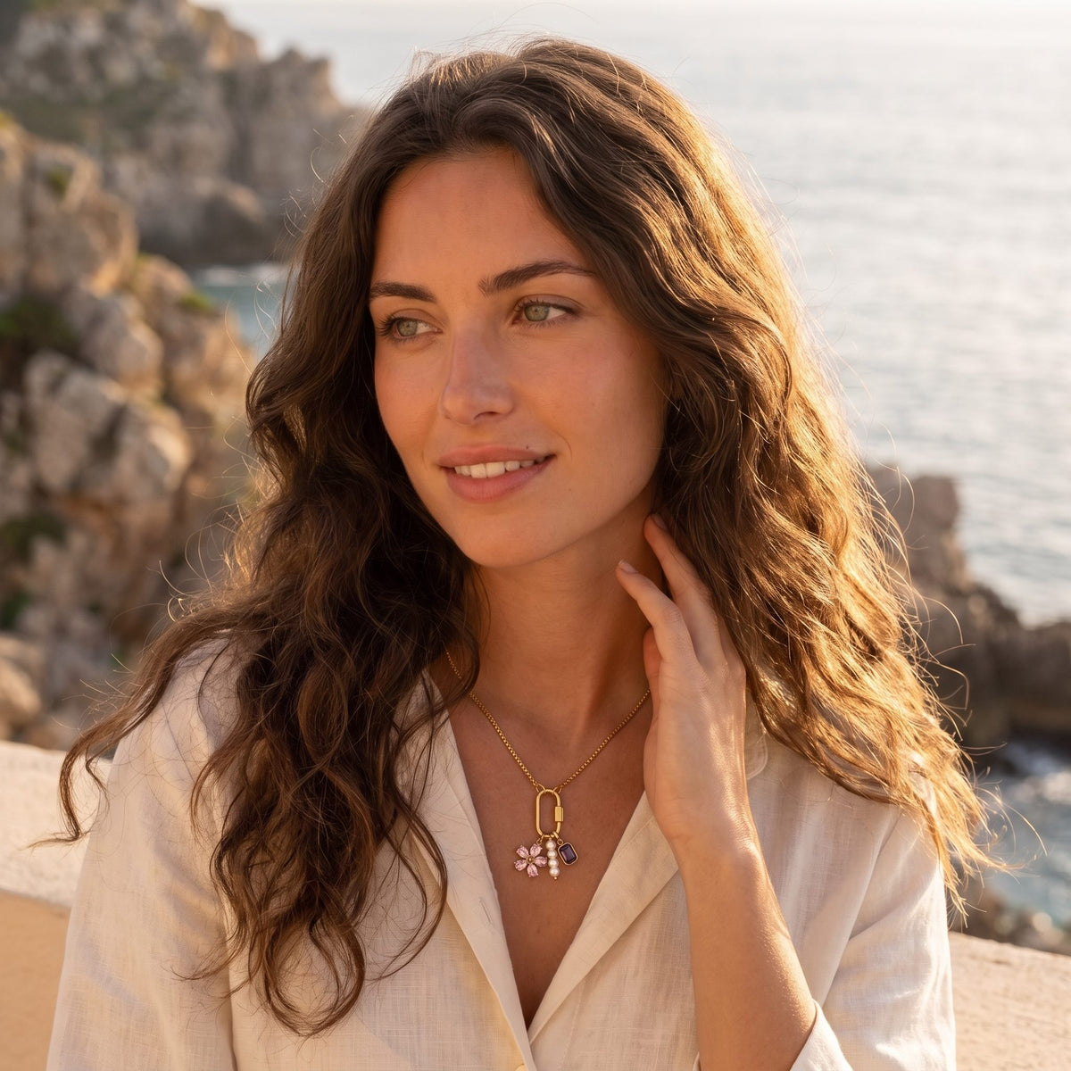 Woman by the sea at golden hour wearing the Lilou flower charm gold necklace