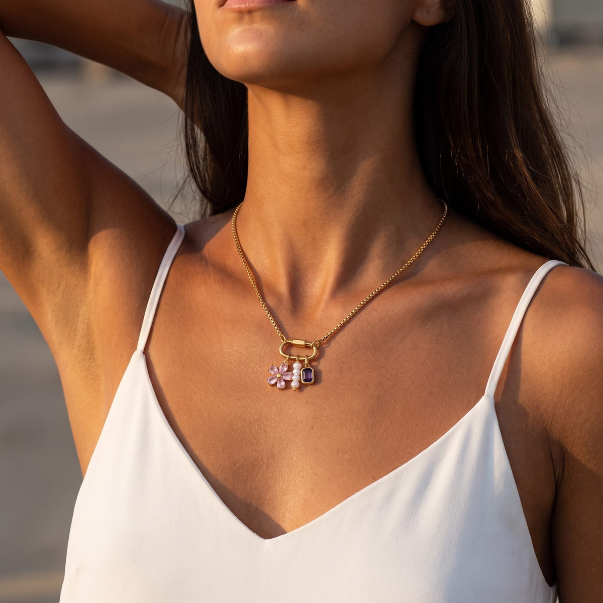 Woman in a white camisole wearing the Lilou flower charm gold necklace in warm evening light