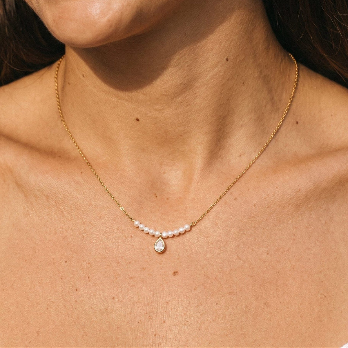 Woman wearing the Lisette pearl bar gold necklace at the collarbone