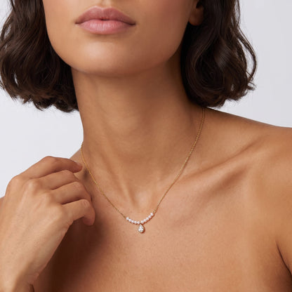 Woman wearing the Lisette pearl bar gold necklace at the collarbone while touching her neck