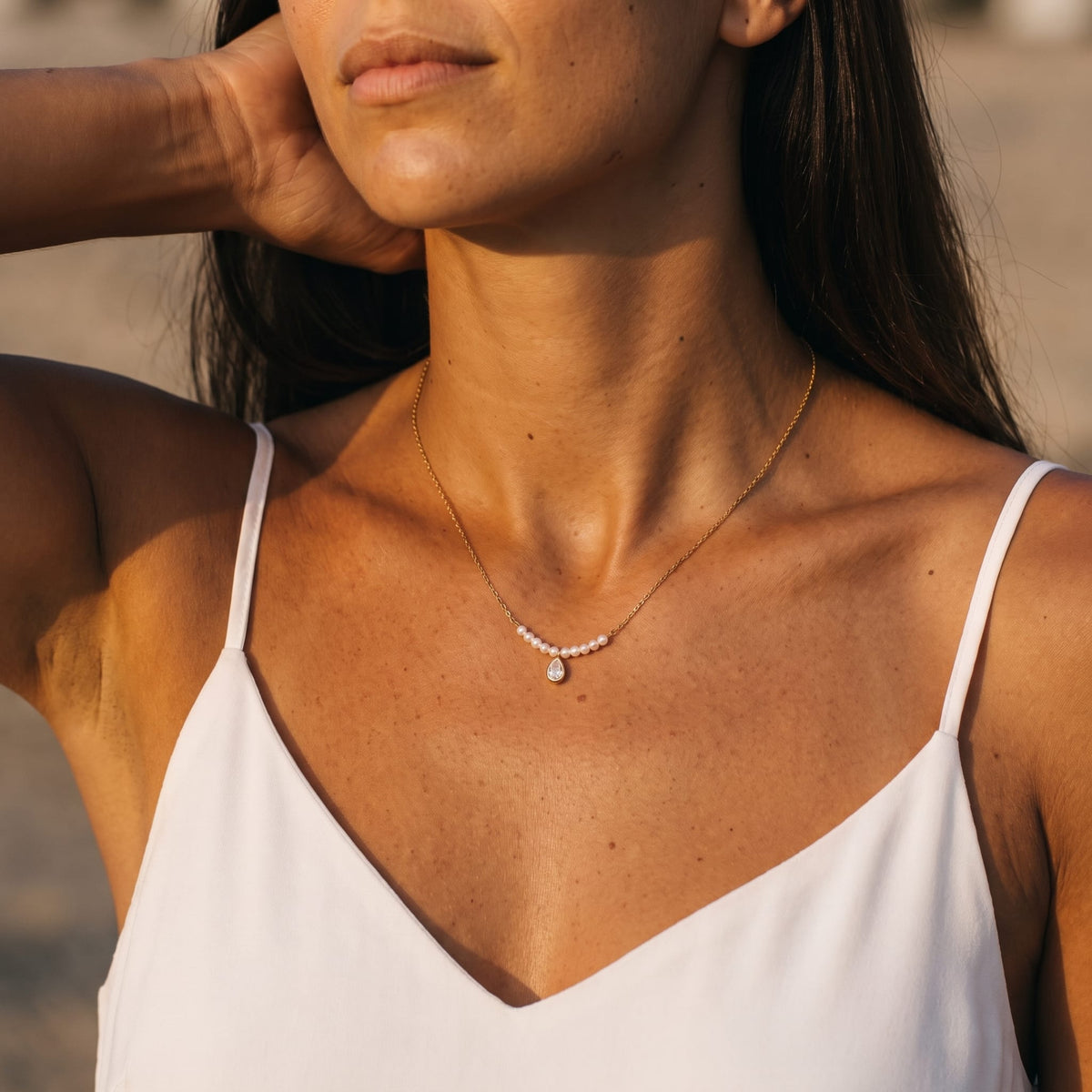 Woman wearing the Lisette pearl bar gold necklace at the collarbone in a white camisole