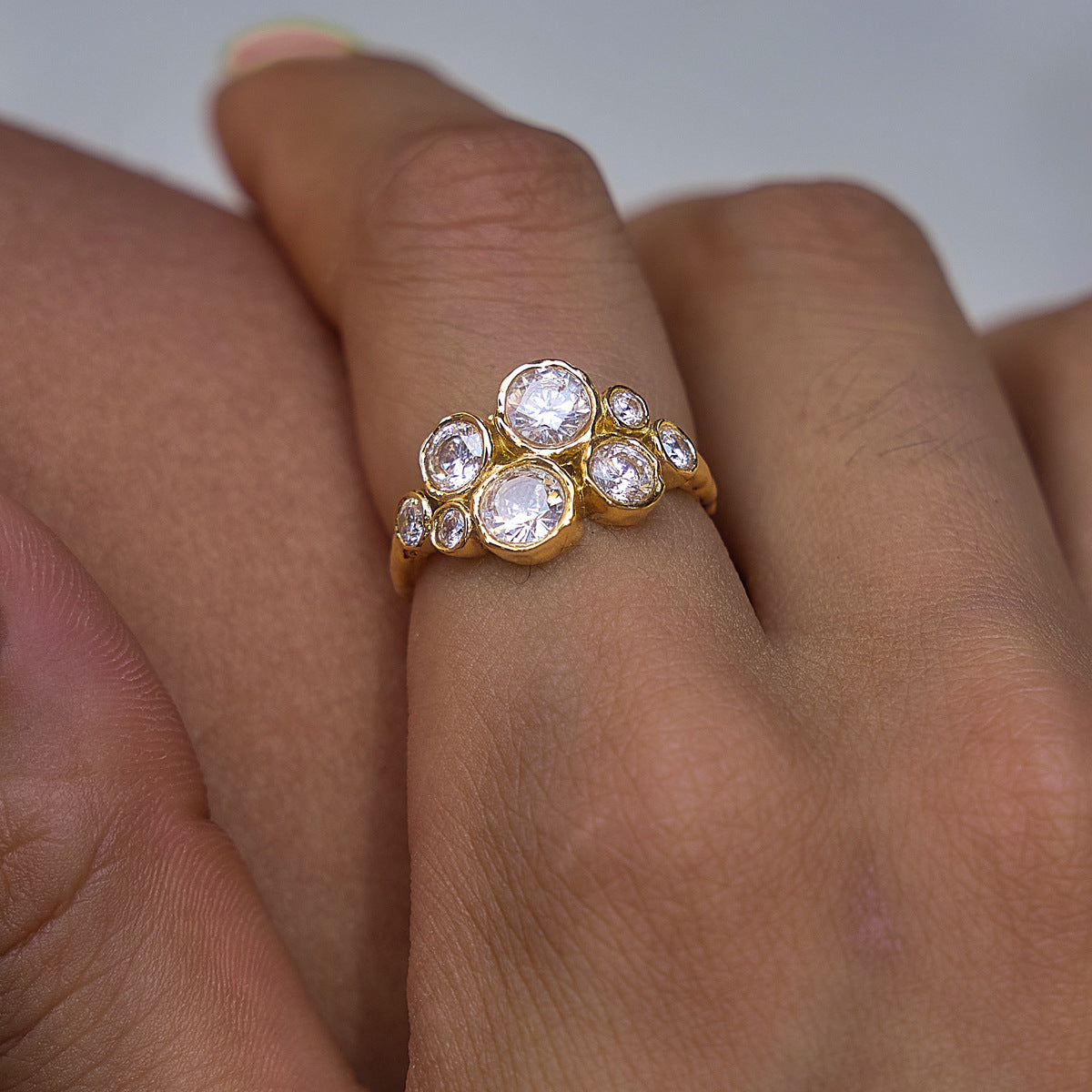 Close-up of a finger wearing the Louise bubble cluster gold ring