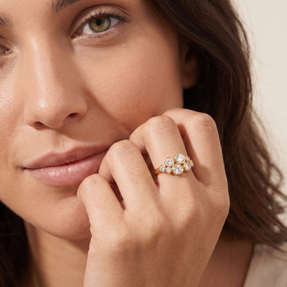 Woman wearing the Louise bubble cluster gold ring on the hand with cheek resting on her fingers