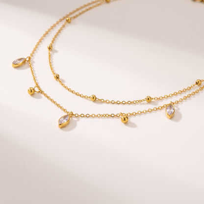 Lucette satellite chain gold necklace on a off-white surface featuring delicate dangling charms