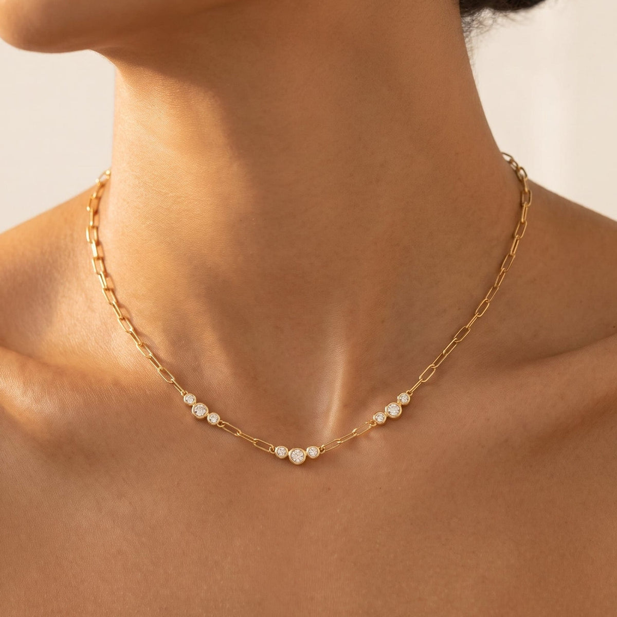 Woman wearing the Lucienne paperclip crystal gold necklace at the collarbone
