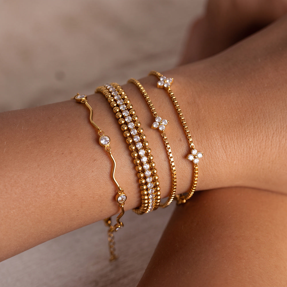 Luna wave crystal bracelet stacked on the wrist with beaded tennis and clover box chain bracelets