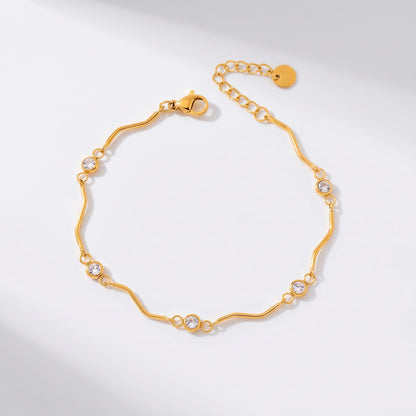 Luna wave crystal gold bracelet on a white surface with wavy links and round zircons