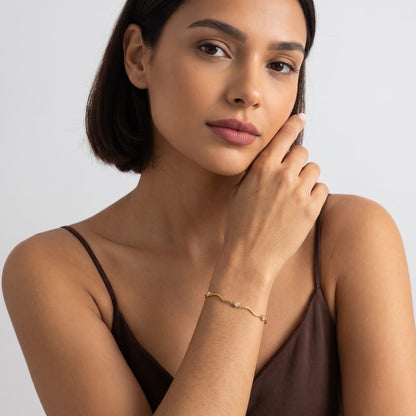 Woman wearing the Luna wave crystal gold bracelet on the wrist posing in a brown top