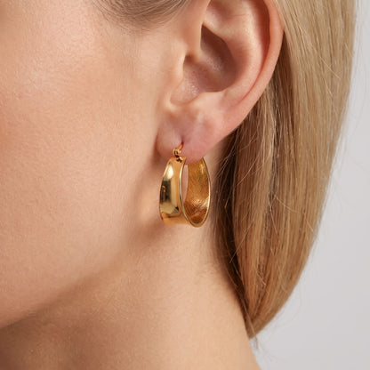 Woman wearing the Lyla wide flat gold hoop with a brushed inner face