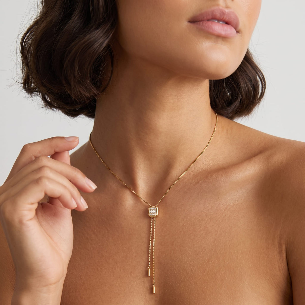 Woman wearing the Maëlys crystal slider gold necklace at the throat with hand near jawline