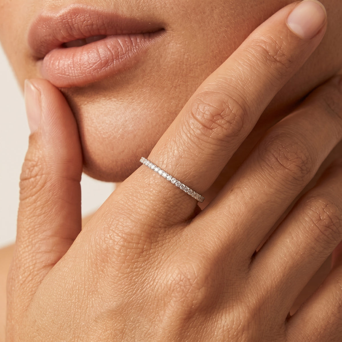 Woman wearing the Ariana pavé silver ring, a slim band lined with tiny crystals, fingers at her lips